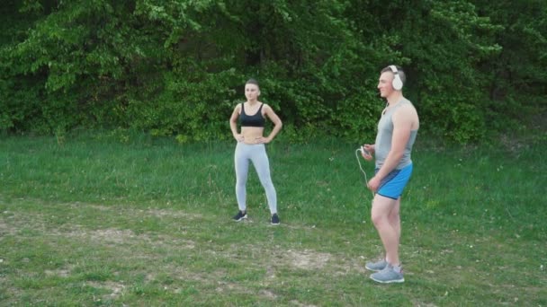 Girl doing a warm-up and a guy wearing headphones — Stock Video