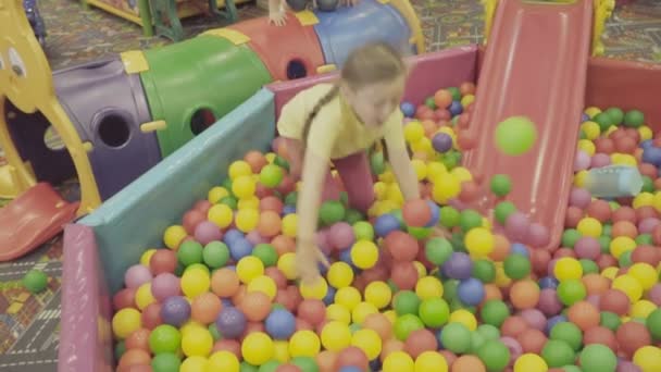 Дети играют в большой куче мячей — стоковое видео