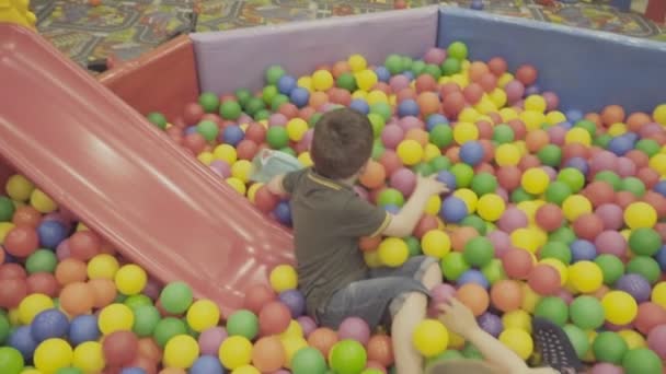 Kinder spielen in einem großen Ballhaufen — Stockvideo