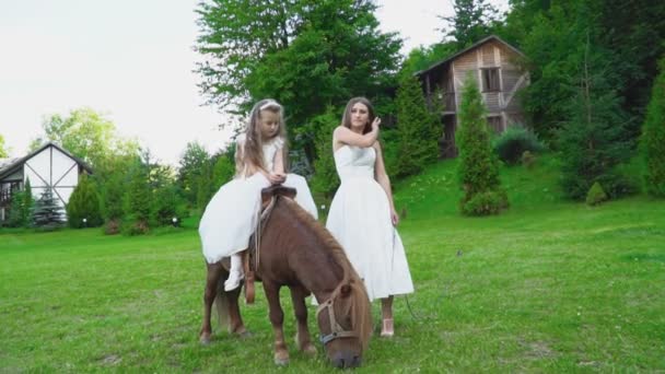 Mère roule sa fille sur un poney — Video