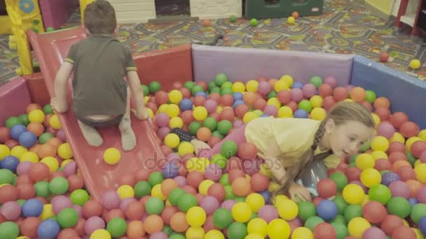 Barnen leker i en stor hög av bollar — Stockvideo