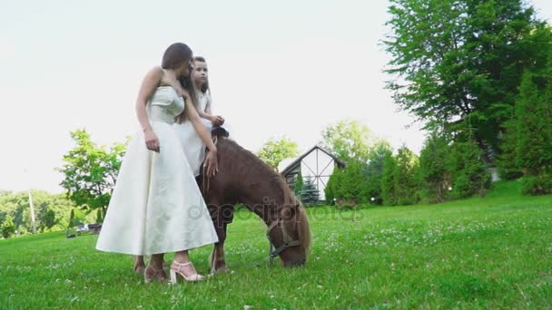 Madre enrolla a su hija en un pony — Vídeos de Stock