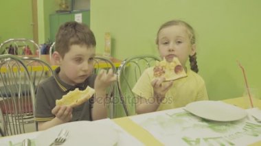 Çocuklar pizza yer.