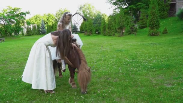 Мать катит свою дочь на пони — стоковое видео