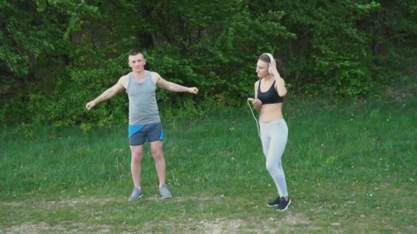 Ten chlap dělá warm-up, zatímco dívka má na sobě sluchátka — Stock video