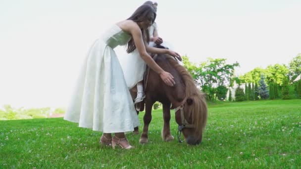 Moeder rolt haar dochter op een pony — Stockvideo