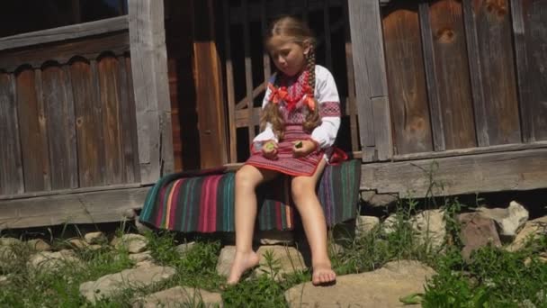 Kleines Mädchen sitzt auf der Veranda des Hauses — Stockvideo