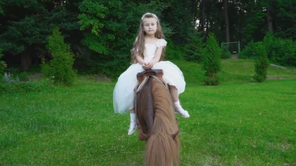 La niña está montando un pony. — Vídeo de stock