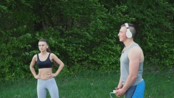Holka dělá warm-up a chlap nosit sluchátka — Stock video