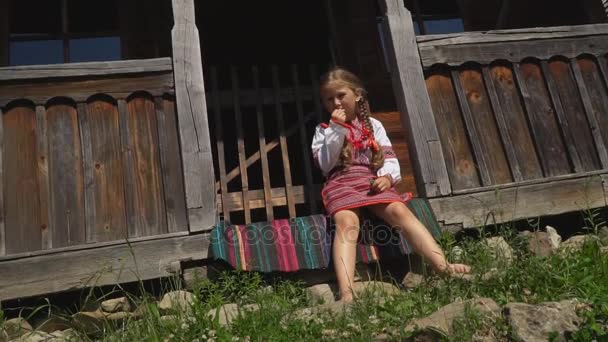 Liten flicka sitter på verandan i huset — Stockvideo