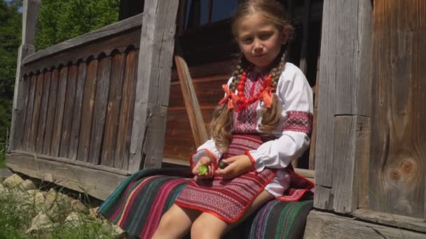 Kleines Mädchen sitzt auf der Veranda des Hauses — Stockvideo