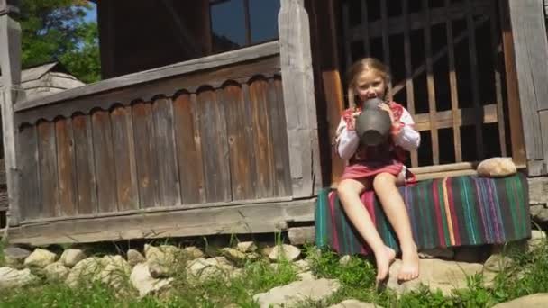 Liten flicka sitter på verandan i huset — Stockvideo