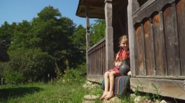 küçük kız evi verandada oturuyor