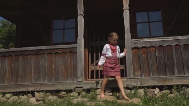 Маленька дівчинка сидить на ганку будинку — стокове відео