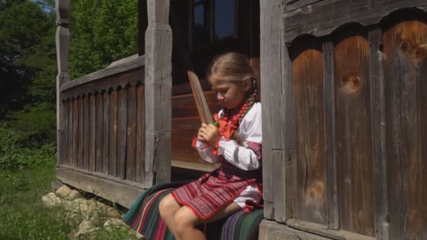 A menina está sentada no alpendre da casa — Vídeo de Stock