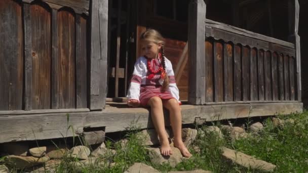 Маленькая девочка сидит на крыльце дома — стоковое видео