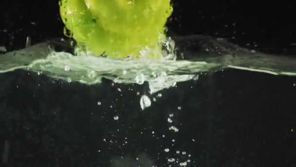 Green pepper drops into the water — Stock Video