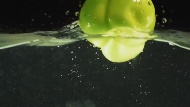 Green pepper drops into the water — Stock Video