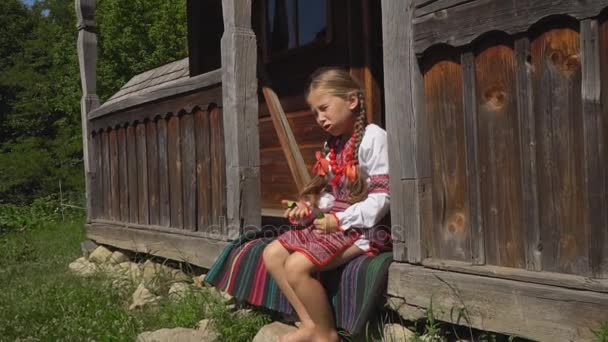A menina está sentada no alpendre da casa — Vídeo de Stock