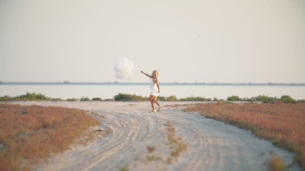 Chica con globos en un camino de tierra — Vídeos de Stock