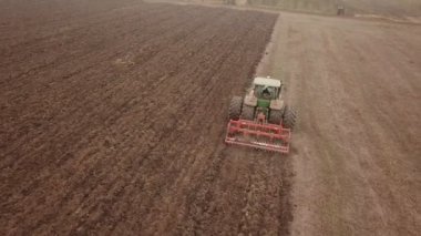 Büyük bir traktör tarlayı sürüyor.