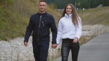 Yanında bir kız olan bir adam göl kenarında yürüyor.
