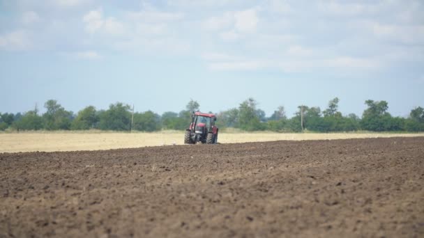 Rode trekker ploegt een veld — Stockvideo