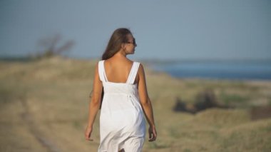 Deniz kıyısında beyaz elbiseli bir kadın.