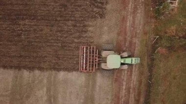 Yeşil traktör toprağı sürüyor.