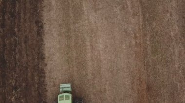 Yeşil traktör toprağı sürüyor.