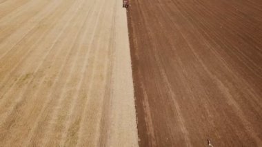 Büyük bir traktör tarlayı sürüyor.