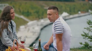 Pikniğe giden çift şarap içer.