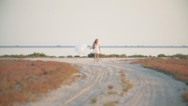 Fille avec des ballons sur une route de sable — Video