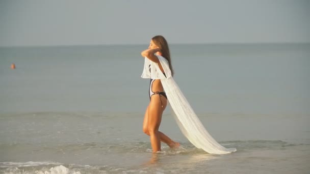 Девушка гуляет у моря у берега — стоковое видео