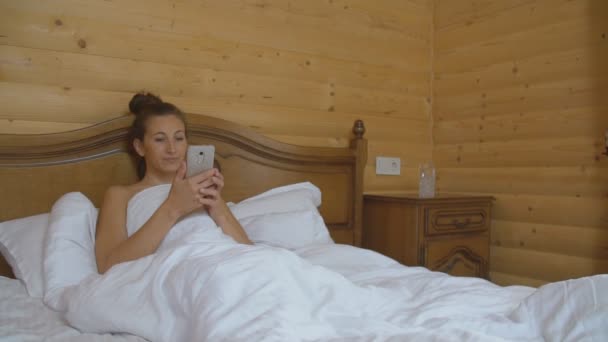 Женщина ложится в постель — стоковое видео