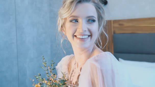 Girl with a bouquet of flowers sitting on the bed — Stock videók