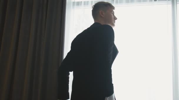 En man står och tittar ut genom fönstret — Stockvideo