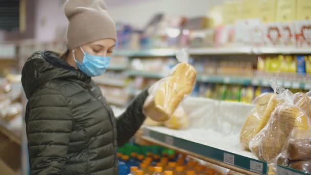 Vrouw met medisch masker koopt brood — Stockvideo