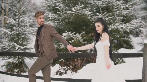 Débilmente vestido pareja cabalgando en la nieve — Vídeo de stock