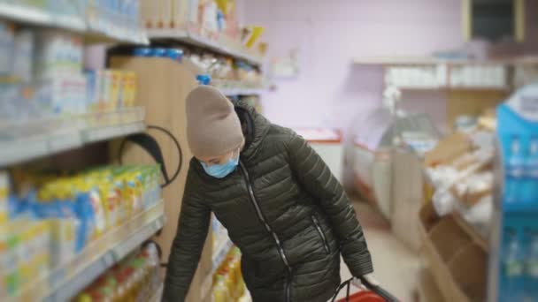 Wanita bertopeng medis berjalan antar baris di supermarket — Stok Video