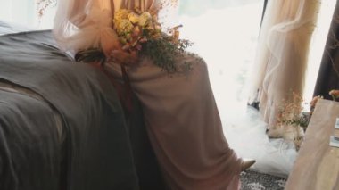 Bir buket çiçekli kız yatakta oturuyor.