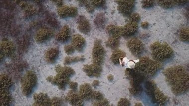 Beyaz elbiseli kız sahilde yürüyor.