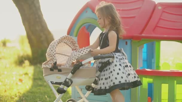 Criança brinca com um carrinho de criança — Vídeo de Stock