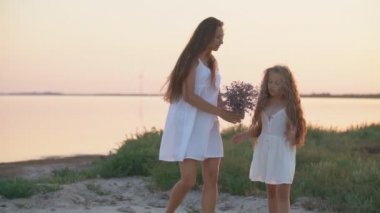 Anne ve kızı deniz kenarında geziniyorlar.