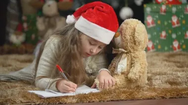 Çocuk Noel Baba 'ya mektup yazıyor.