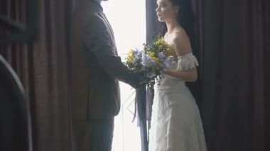 Çift pencerenin yanında duruyor.