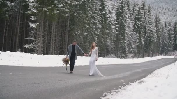 Koppel wandelen op een weg in een bos — Stockvideo