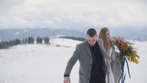 Pareja caminando sobre un césped cubierto de nieve — Vídeo de stock