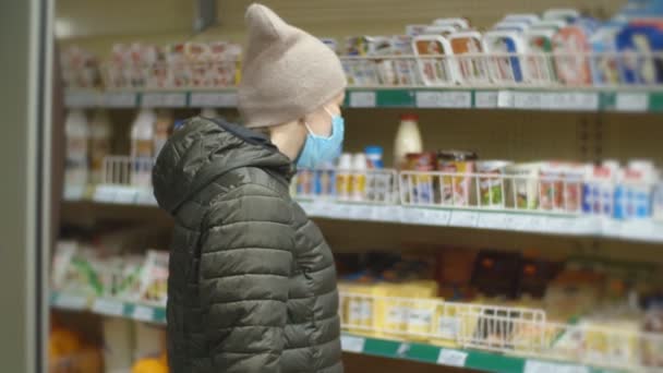 Mulher com máscara protetora escolhe produtos lácteos — Vídeo de Stock