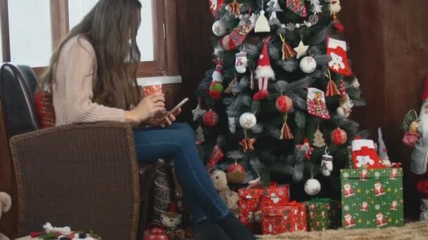 Frau sitzt neben Weihnachtsbaum — Stockvideo